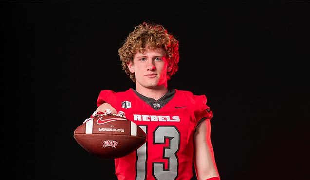 Nash wearing football uniform, holding a football in front of a black background