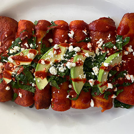 Healthy enchiladas with sliced avocados on top.