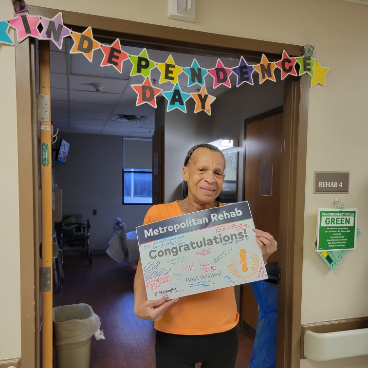 Claudette Dunnaway standing in hospital room doorway under sign reading "Independence Day"