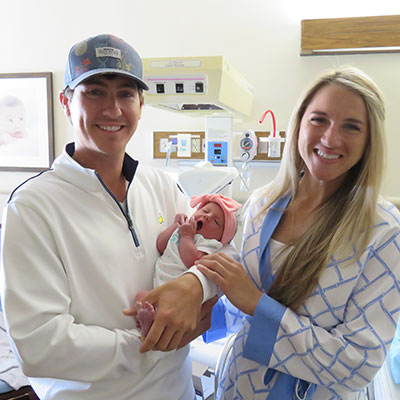 Couple Cole and Christian pose with newborn daughter Elle.