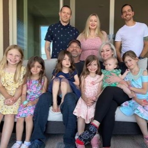Heart attack survivor Laura Obenchain poses on a couch with her family on an outdoor patio.