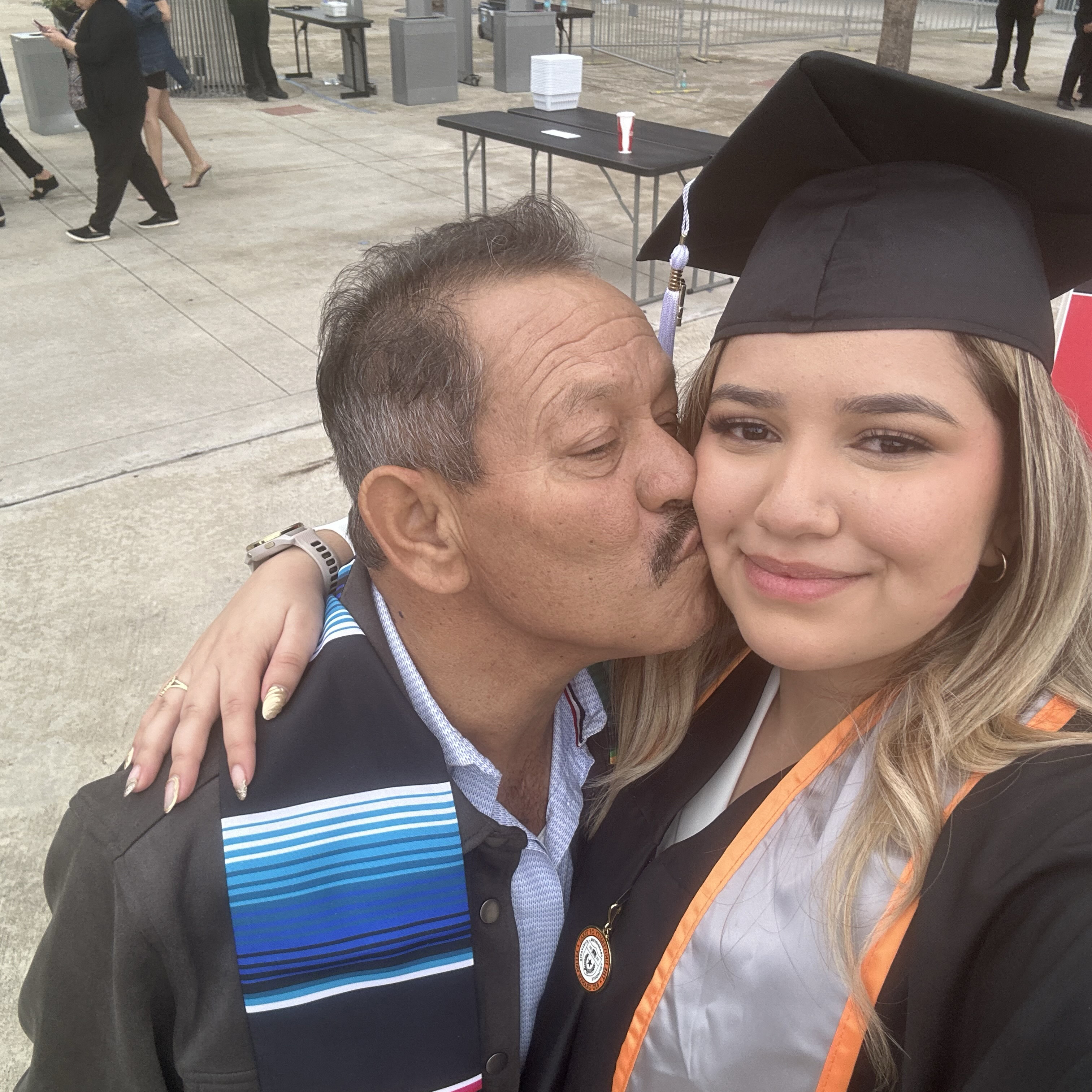 Itzel Guzman being kissed on the cheek by her father at graduation