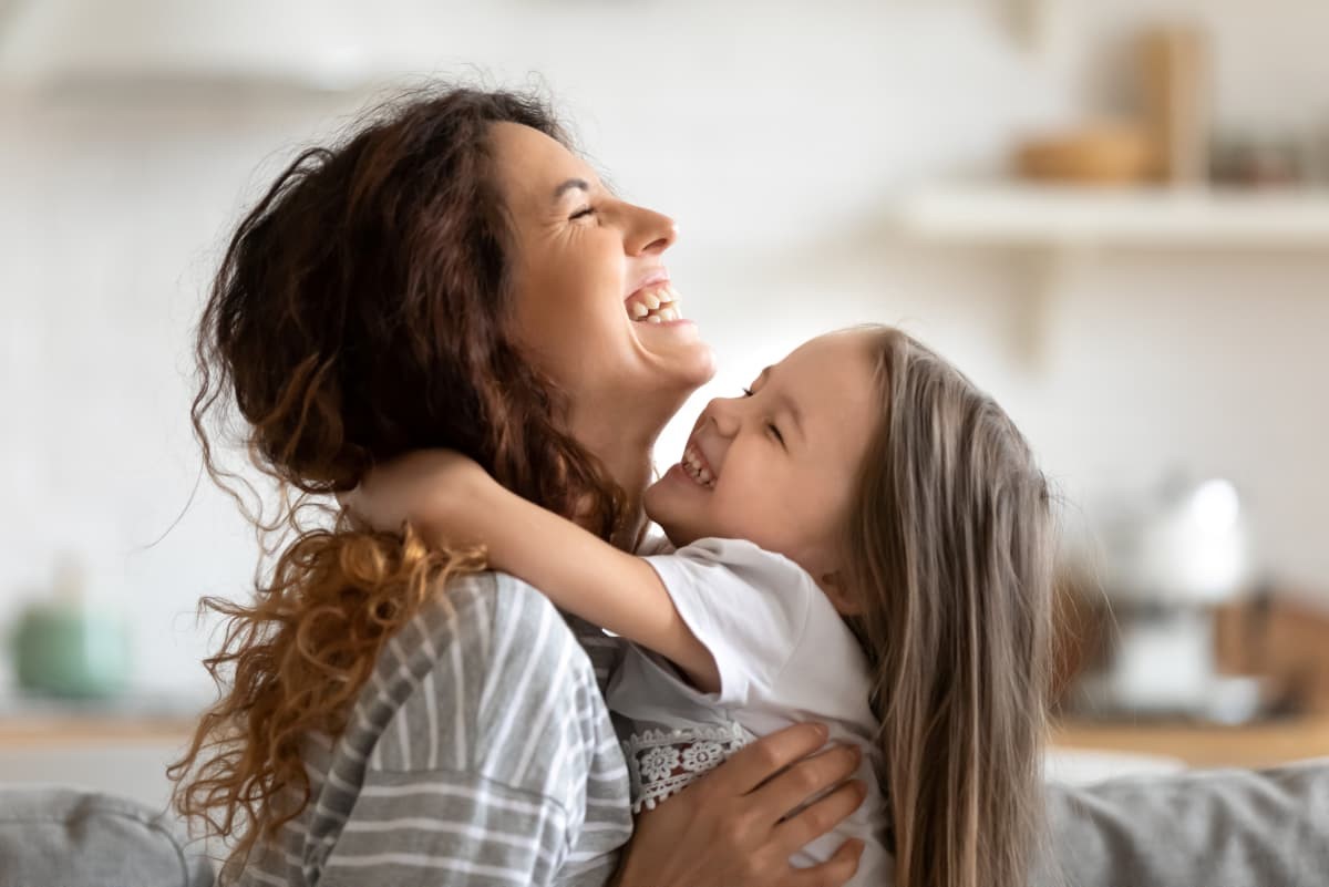 Mother and daughter smiling and hugging.