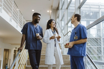 Healthcare providers laugh and talk on a set of stairs.