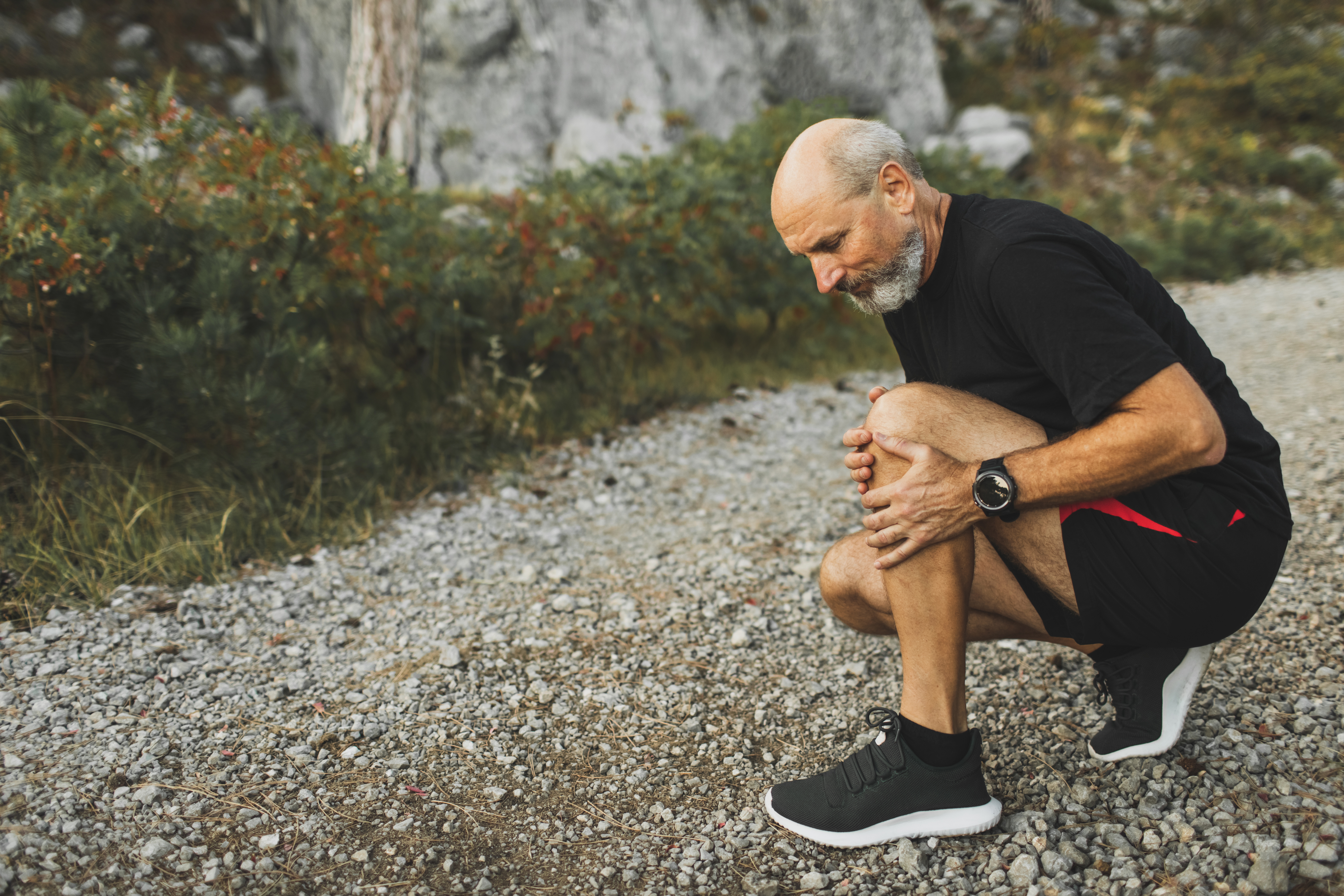 Senior man holding knee by hands and suffering with pain.