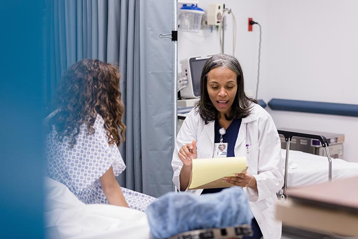 A doctor talking to a patient in a hospital bed.
