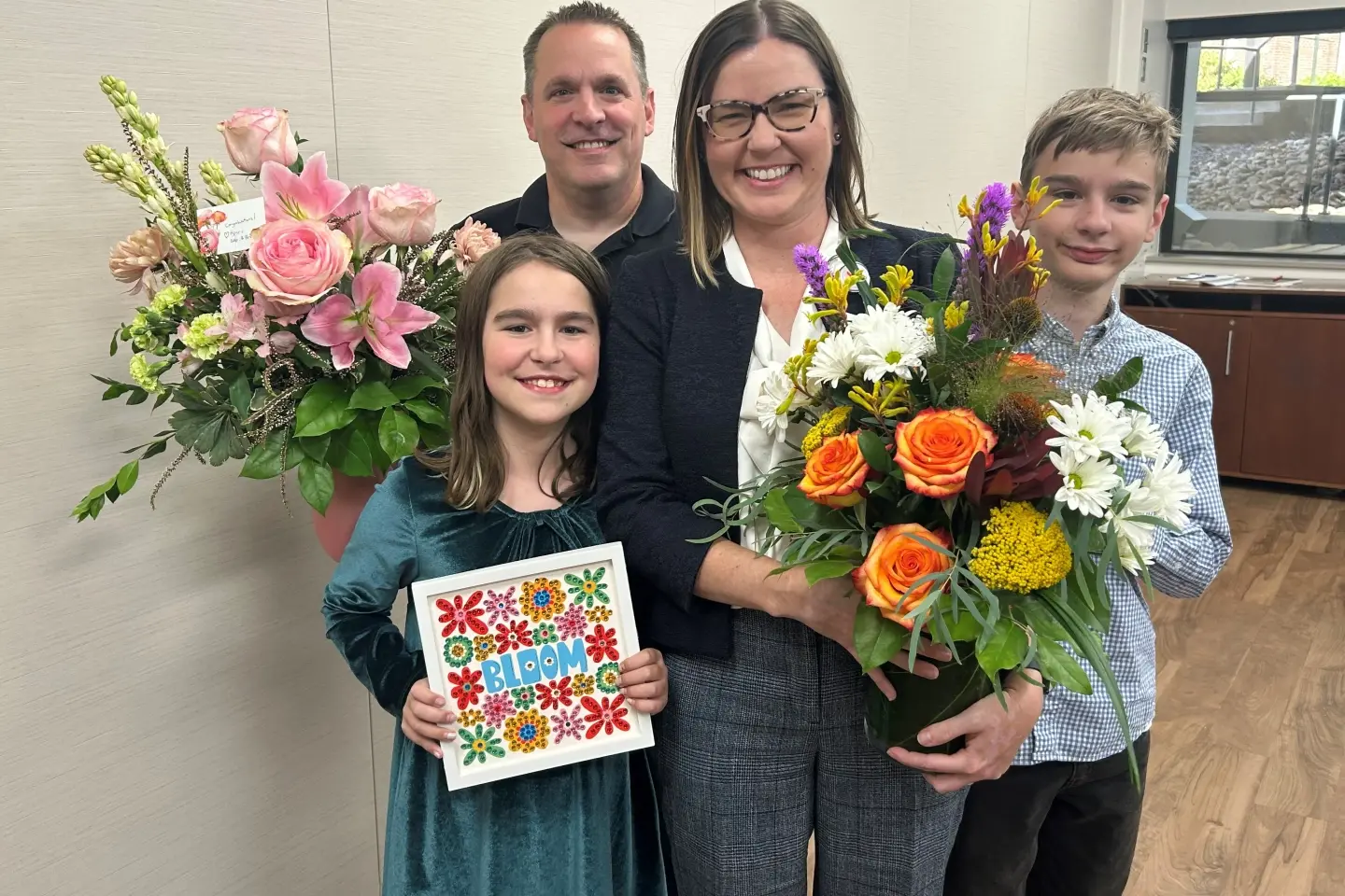 Rachel, holding a bouquet of flowers, with her husband, daughter and son.
