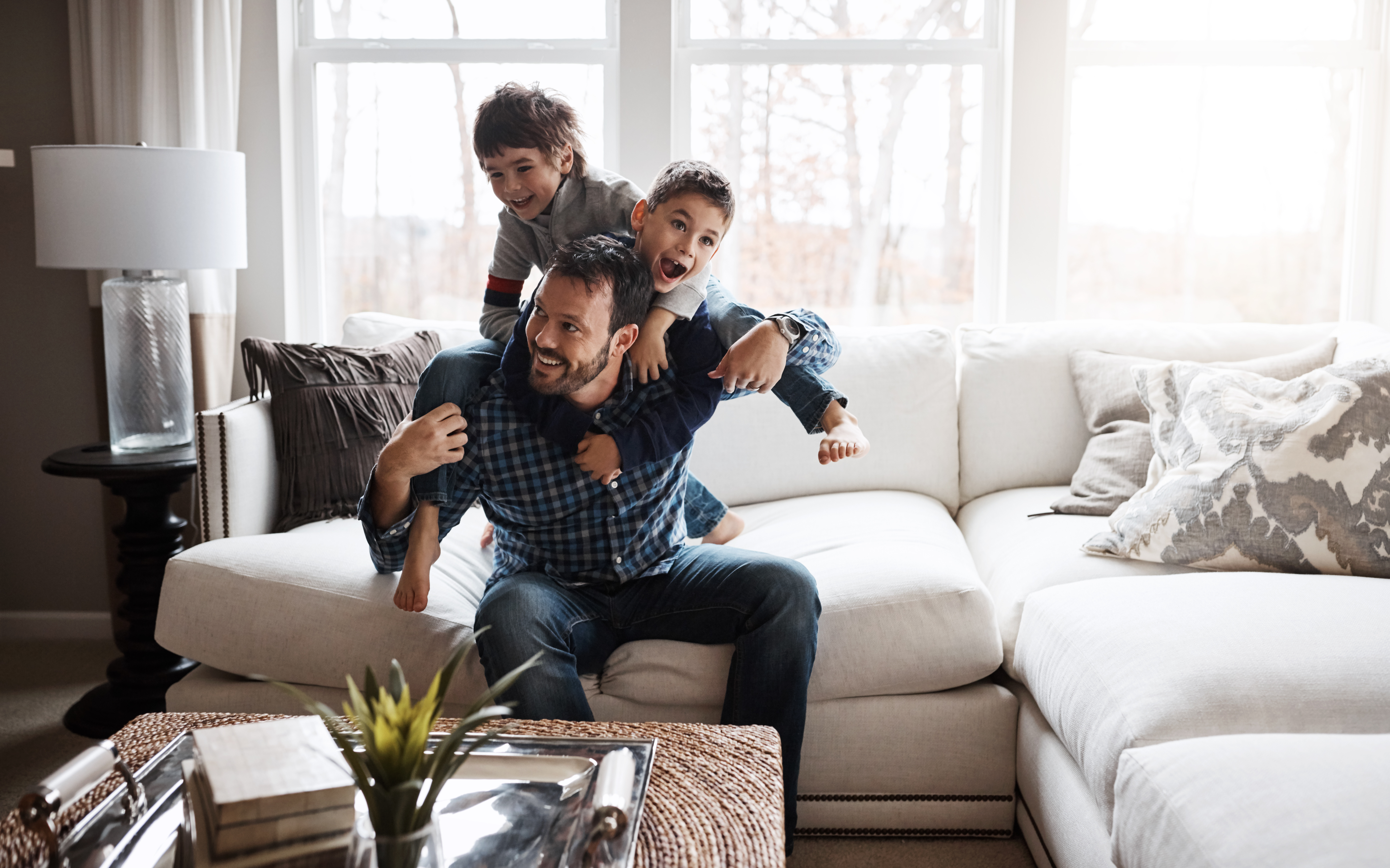 A happy father playing with his two sons in the livingroom.