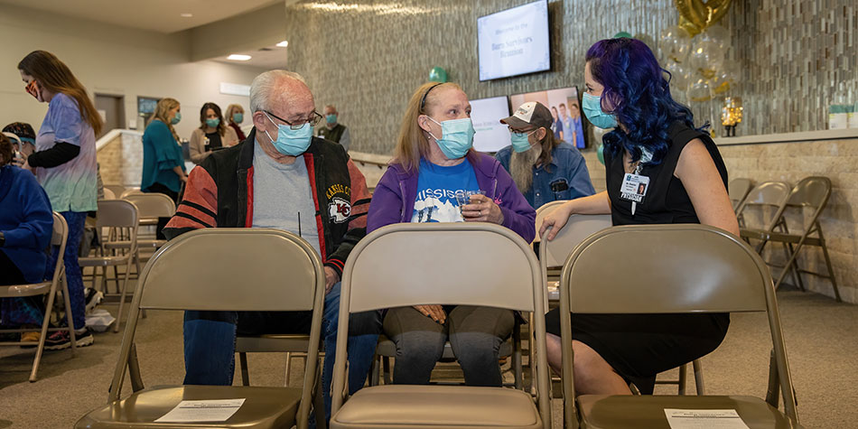 Staff member talking to a man and woman wearing masks.