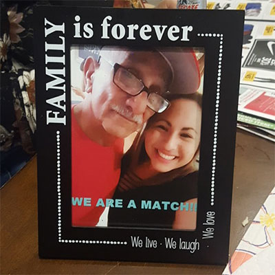 A photo of Deanna and her father Richard Navejar with the words "We are a match" across the lower center in a photo frame that says "Family is Forever."