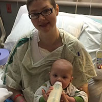 Genny Small sitting on a hospital bed, cradling her baby in her arms.