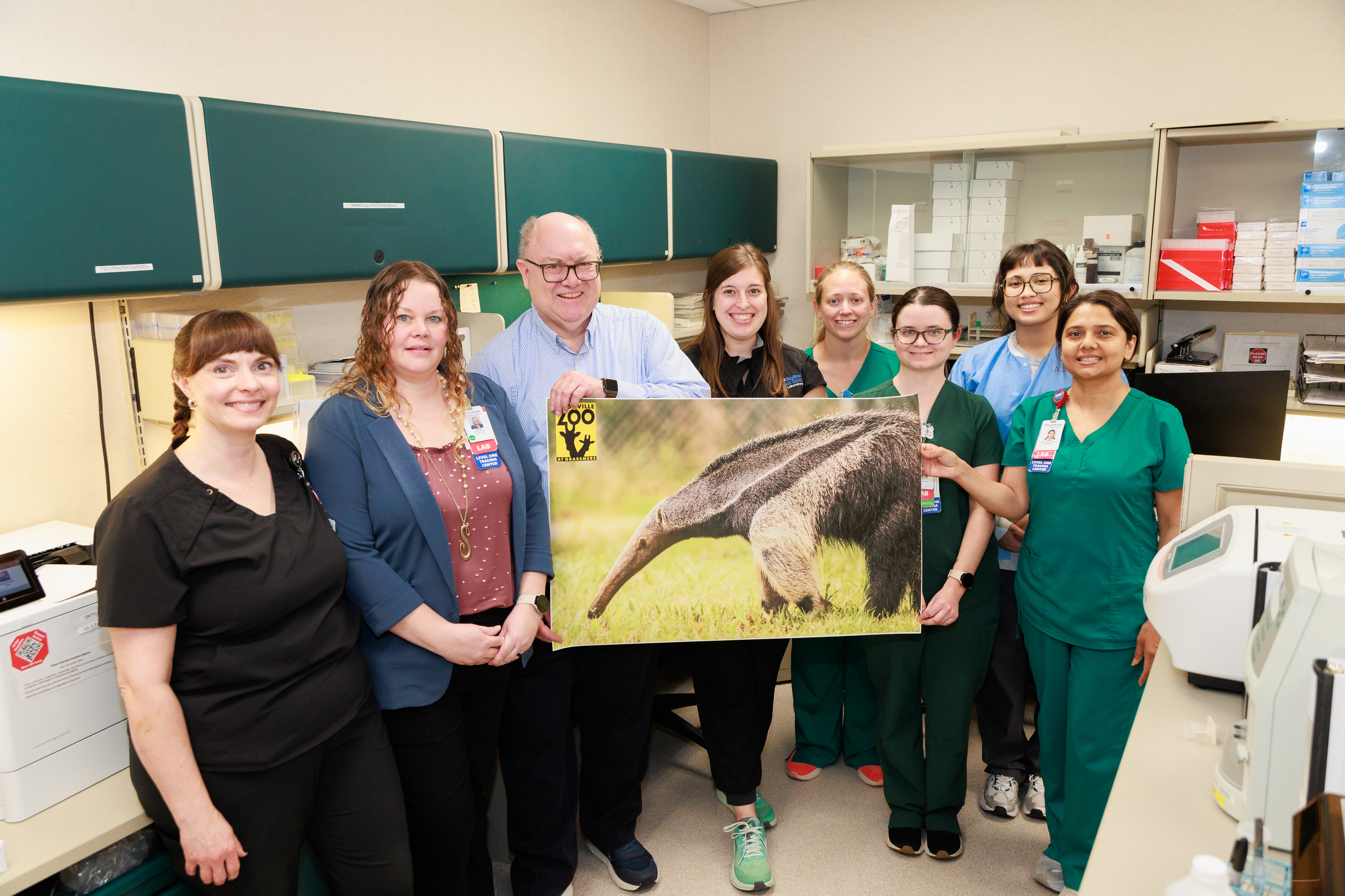Nashville Zoo anteater team holding a picture of an anteater. 