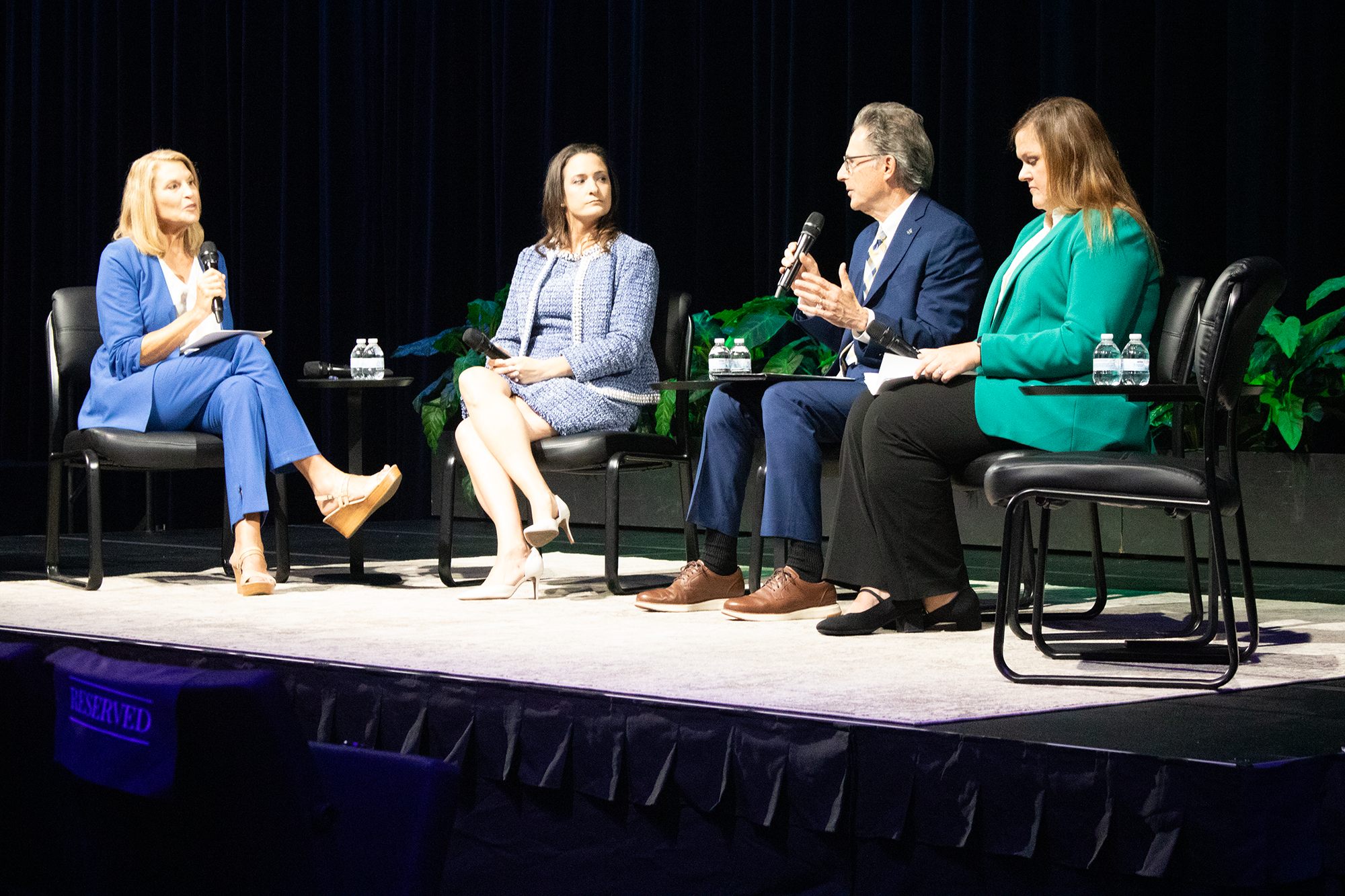 Judy Maggio moderating panel on stage with Beth Vaughn and others