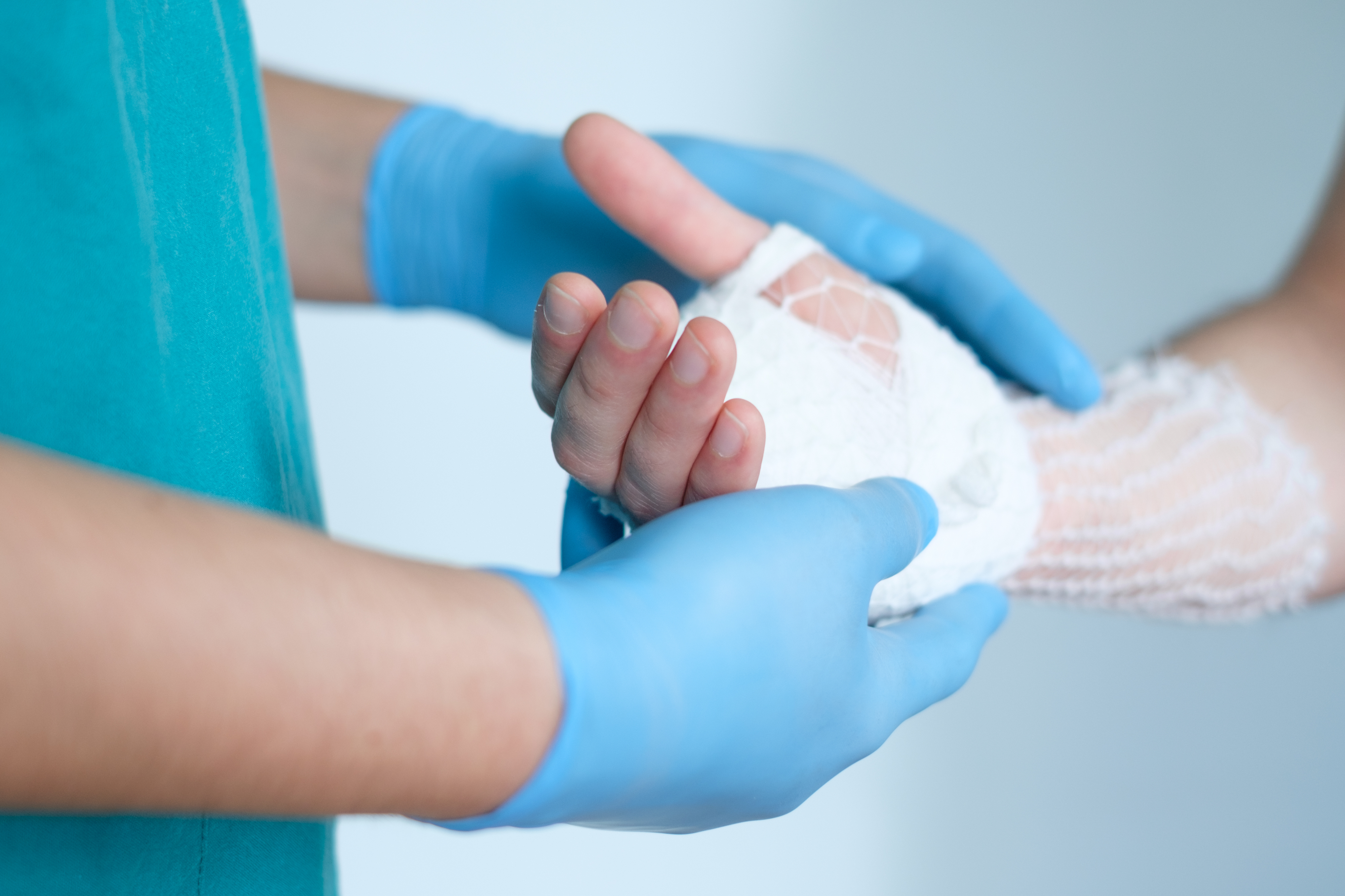 Doctor bandaging the hand of a patient.