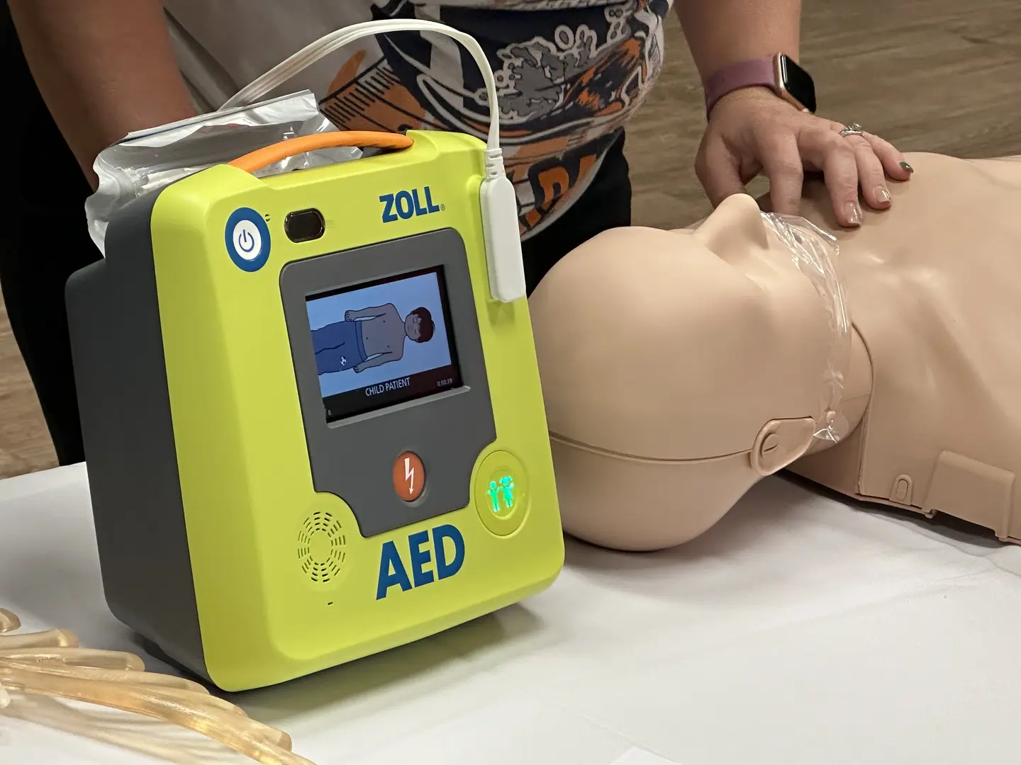 Close up photo of yellow AED device and training manikin