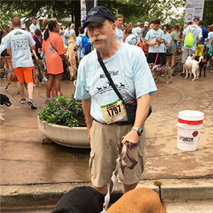 Patient Matthew Wagner wears a baseball cap and holds a leash to his dog.