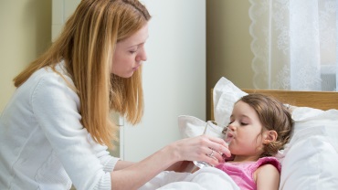 Mother checking a child's temperature with a thermometer.
