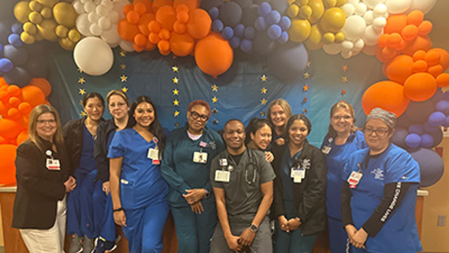 Nurses posing in front of a balloon archway.
