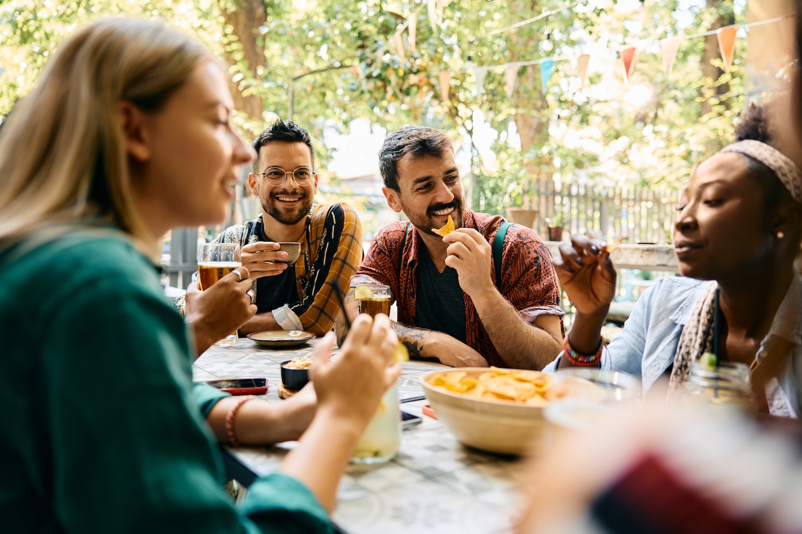 A group of friends laugh and smile while enjoying an outdoor dinner together.