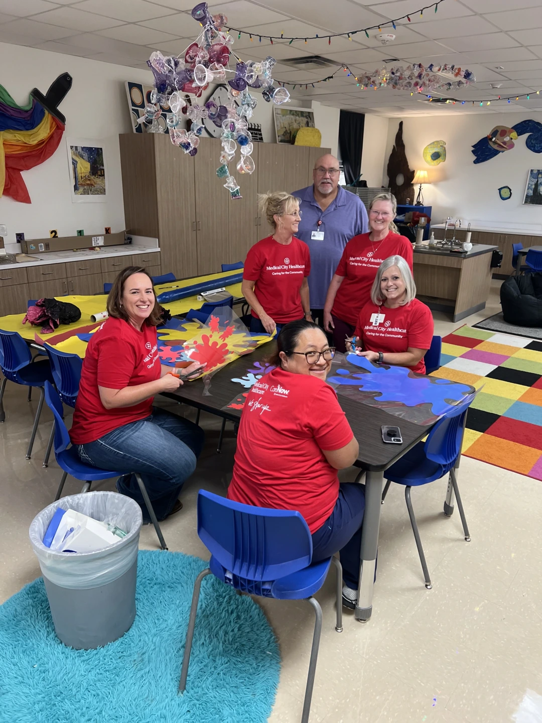 Medical City Decatur colleagues, wearing red “Caring for the Community” T-shirts, help set up a teacher's classroom for the first day of school.