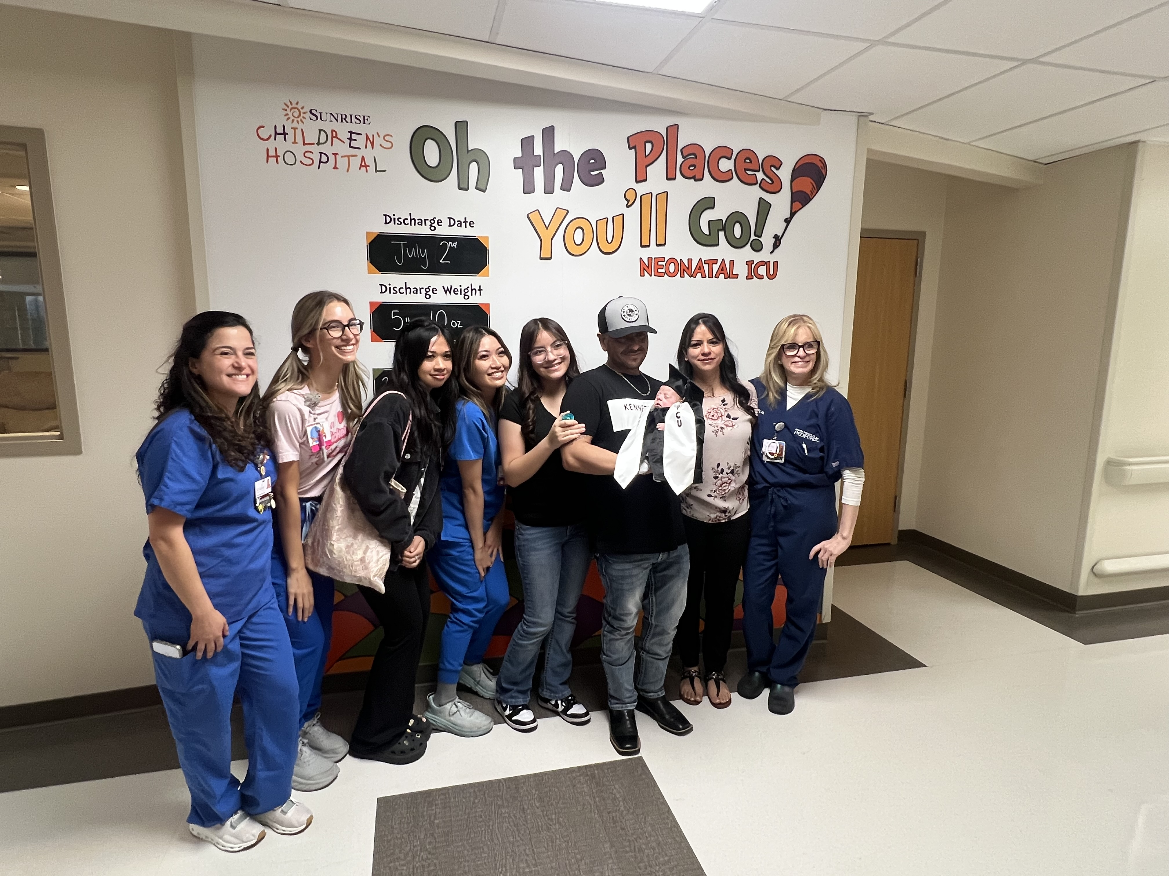 NICU baby surrounded by his family and care team of nurses and doctors. 