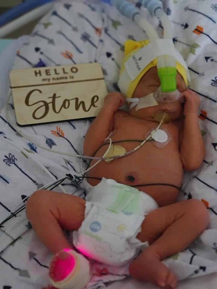 A newborn baby with a "Hello, my name is Stone" sign next to him.