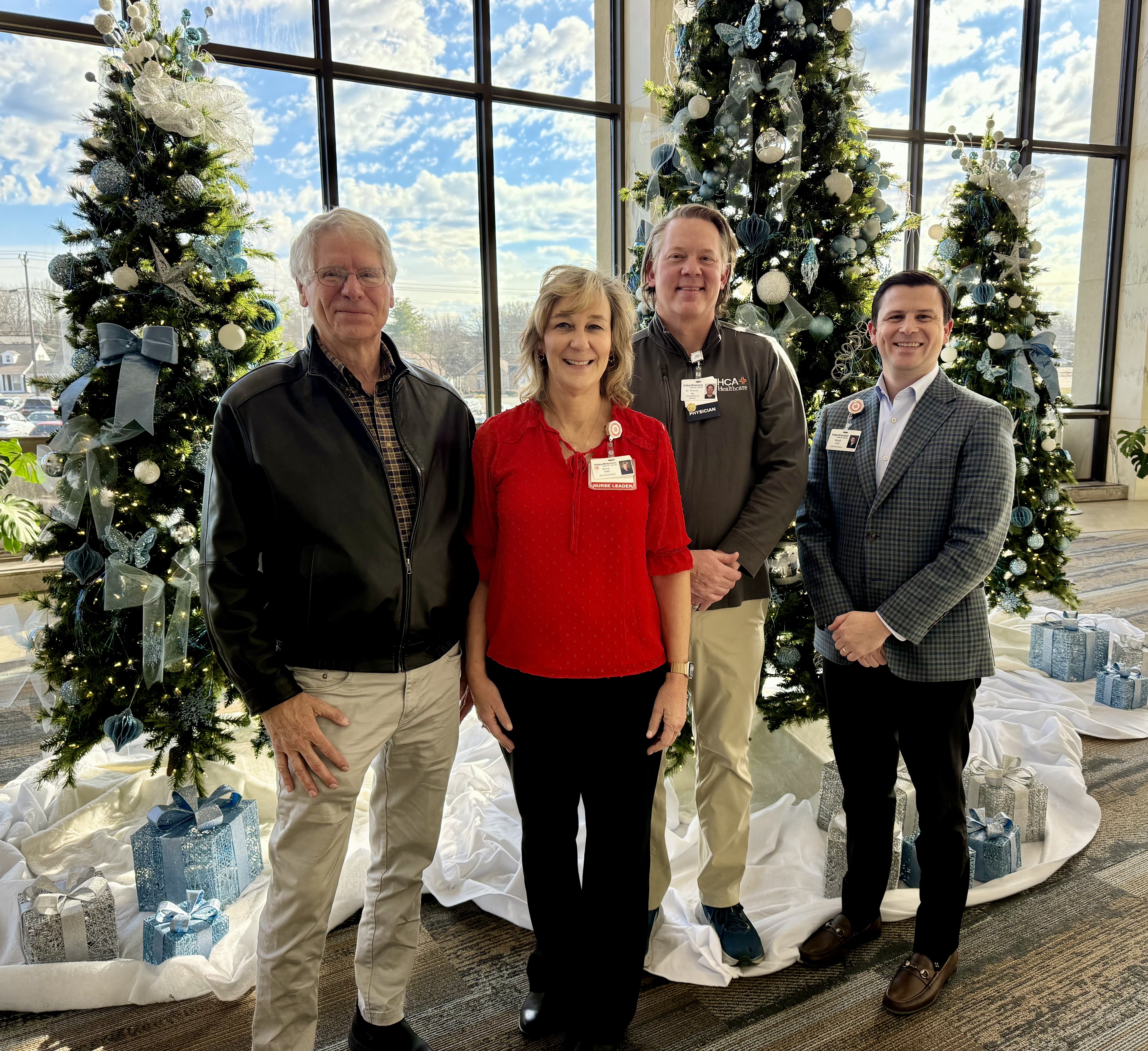 Dr. Gordon, Gina Bullington, Dr. Tincher, and Wyatt Chocklett posing in front of christmas tree decorations.