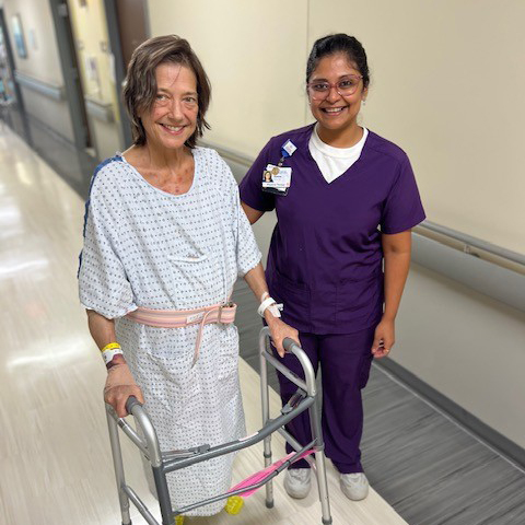 Aparna Iyer standing with patient who is using a walker in hospital hallway