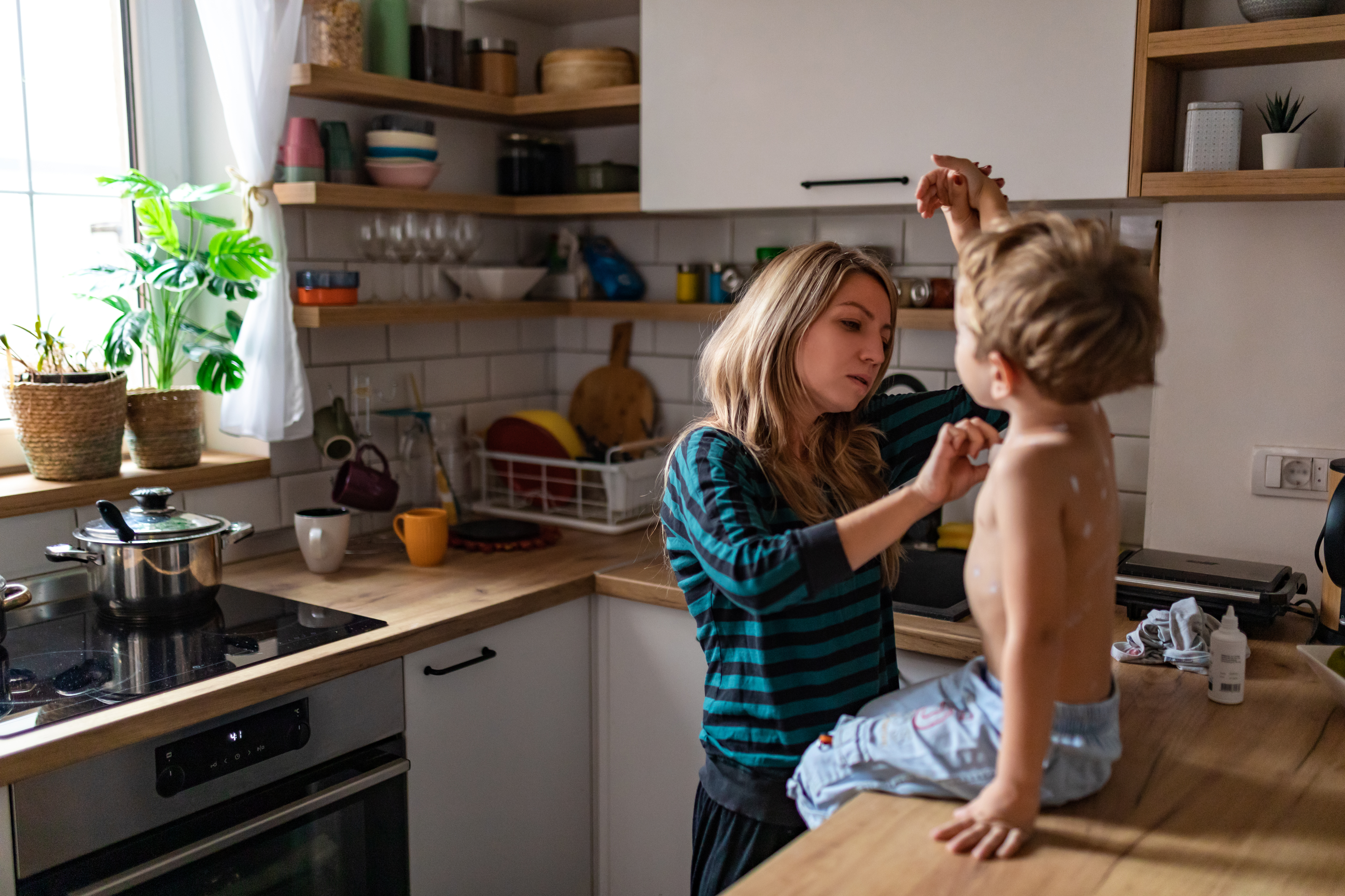 A mother treats a young boy with measles on the kitchen counter.