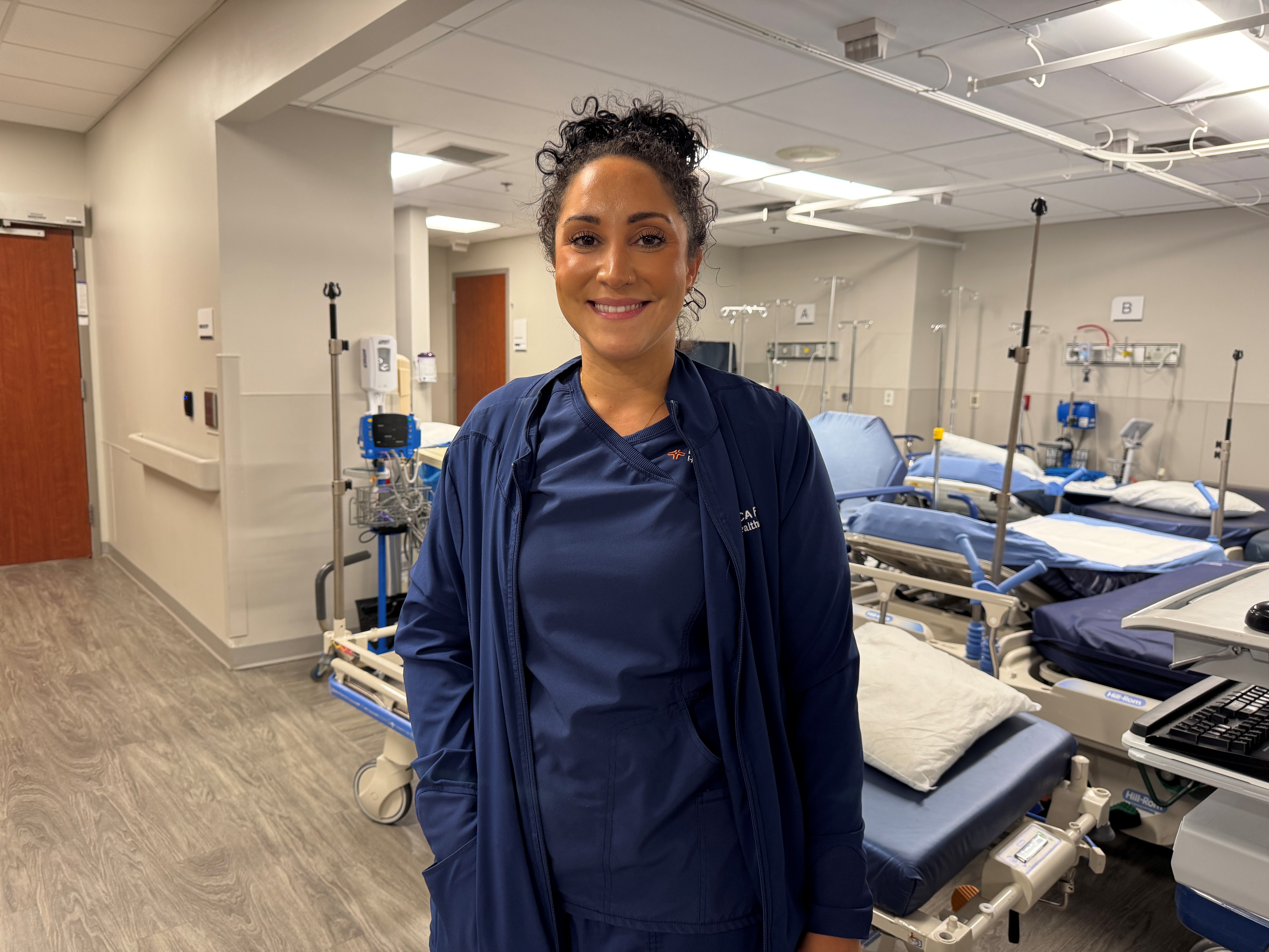 Nurse stands smiling.