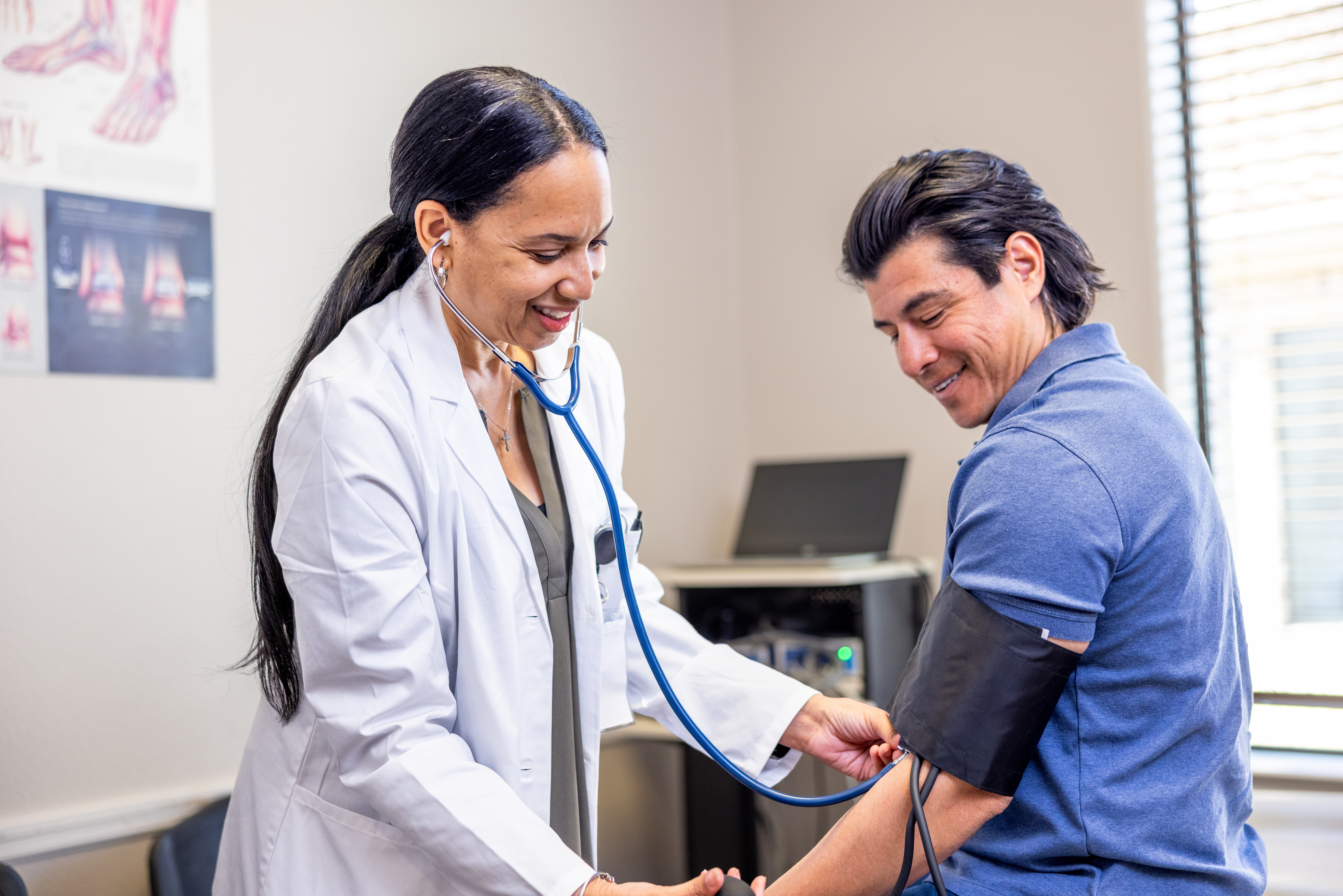 A doctor checks a patient's blood pressure in an examination room.