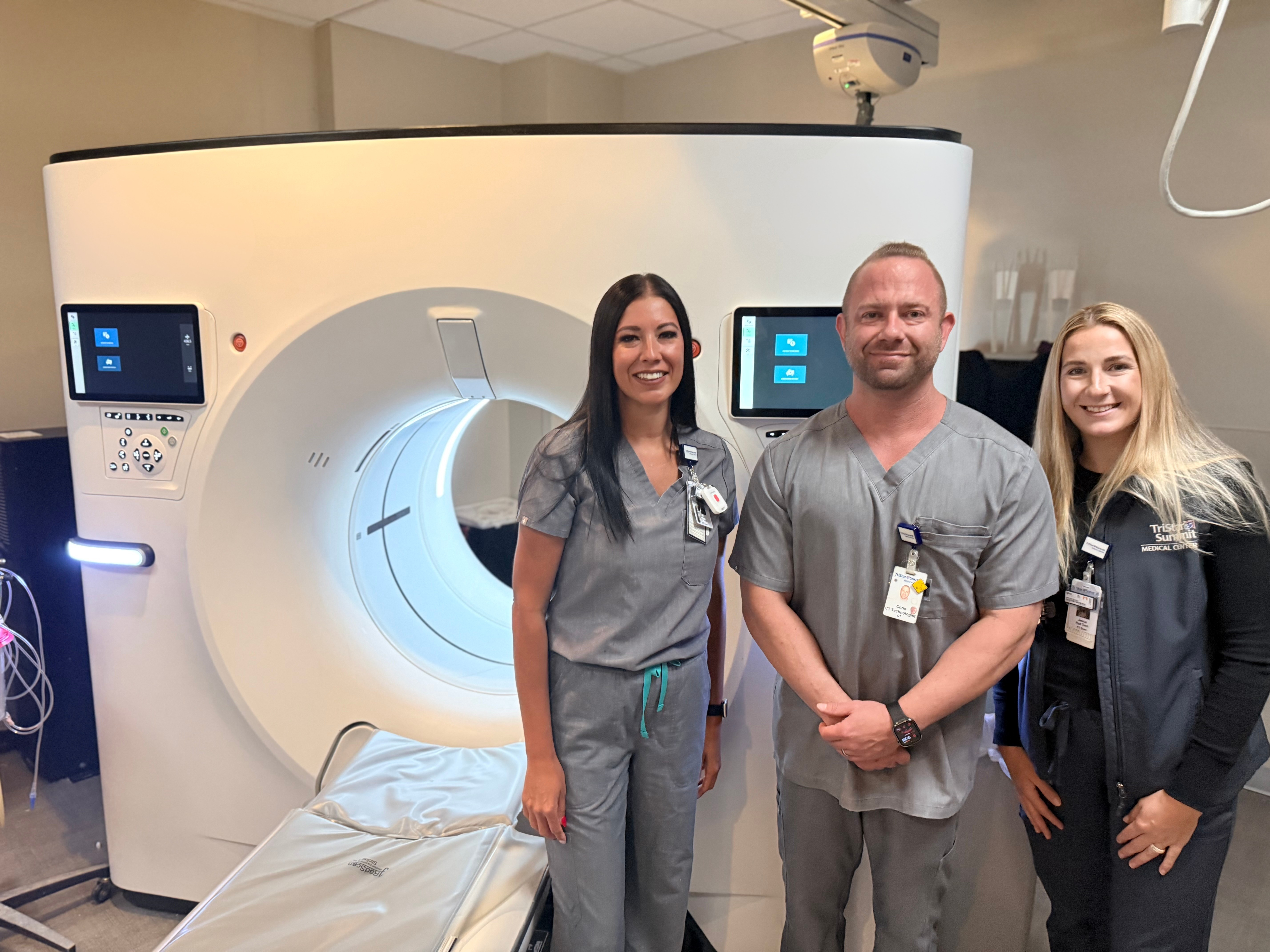 Three Tristar Summit Medical Center healthcare staff members stand beside a CT scanner in a medical imaging room.