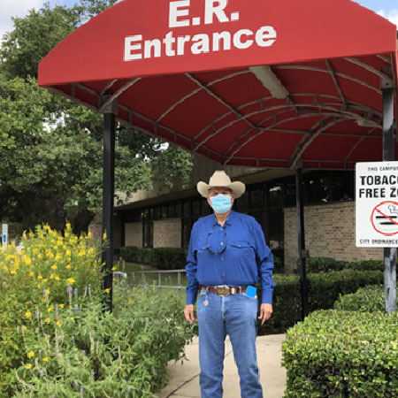 Armando Galindo standing outside of Methodist Hospital's ER entrance, wearing a face mask and a cowboy hat.