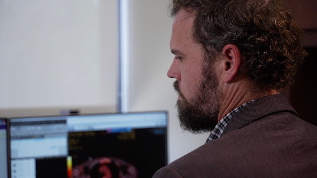 Dr. Luke Mountjoy sitting in front of a monitor.