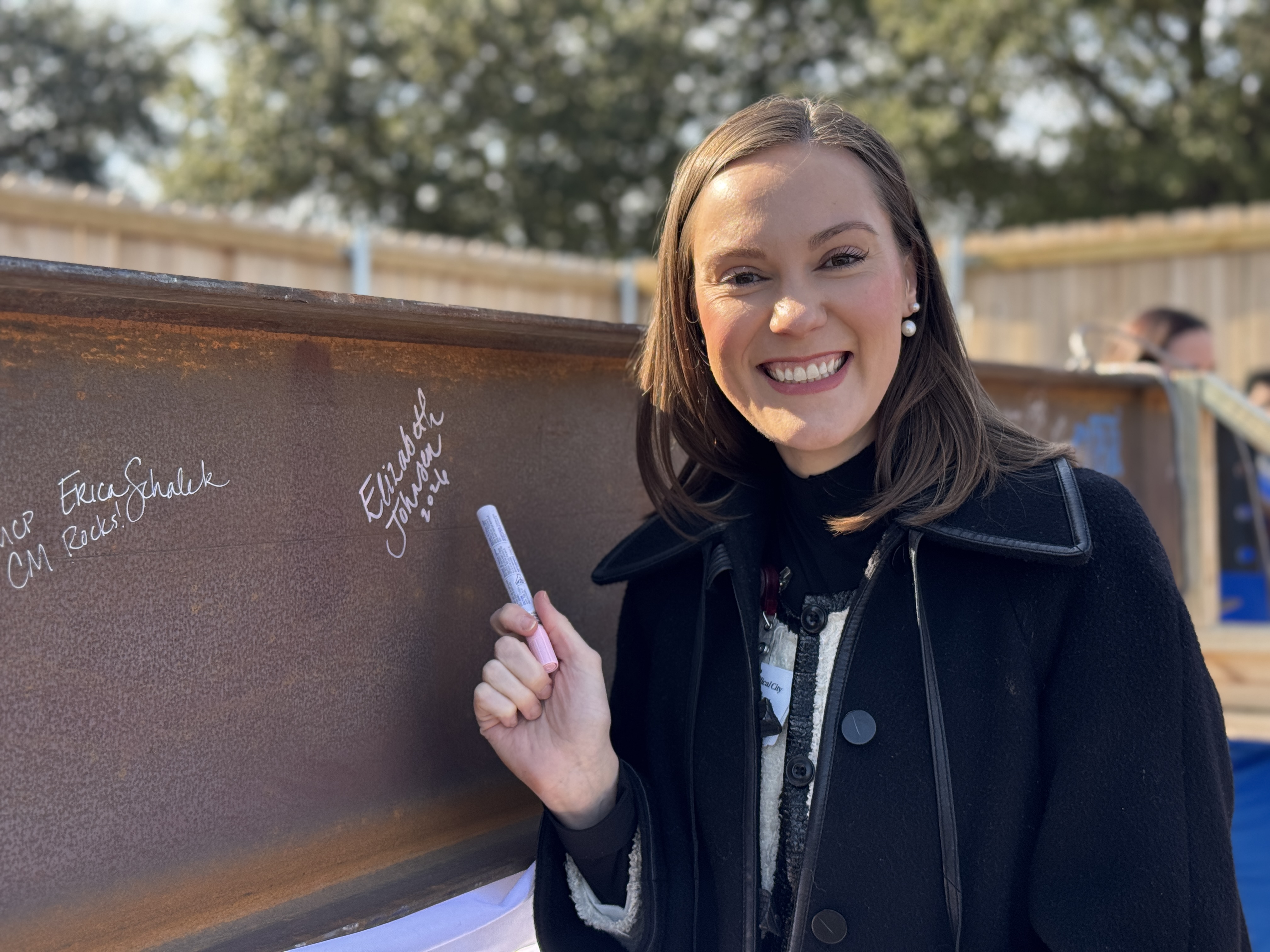 COO Elizabeth Johnsen smiles while pointing to her signature on steel beam.