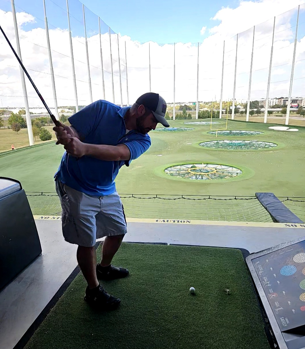 Jerry Farmer taking a golf swing at the driving range.