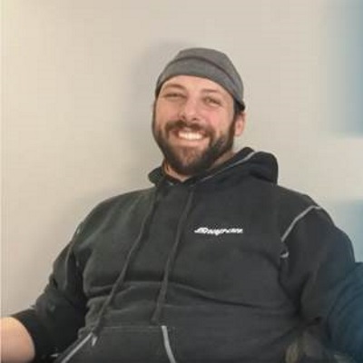 Robert Young smiles while wearing a baseball cap and a black hoodie.