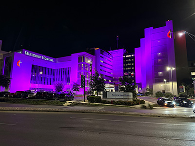 Methodist Hospital exterior with glowing purple lights in honor of Cancer Survivor's Month.
