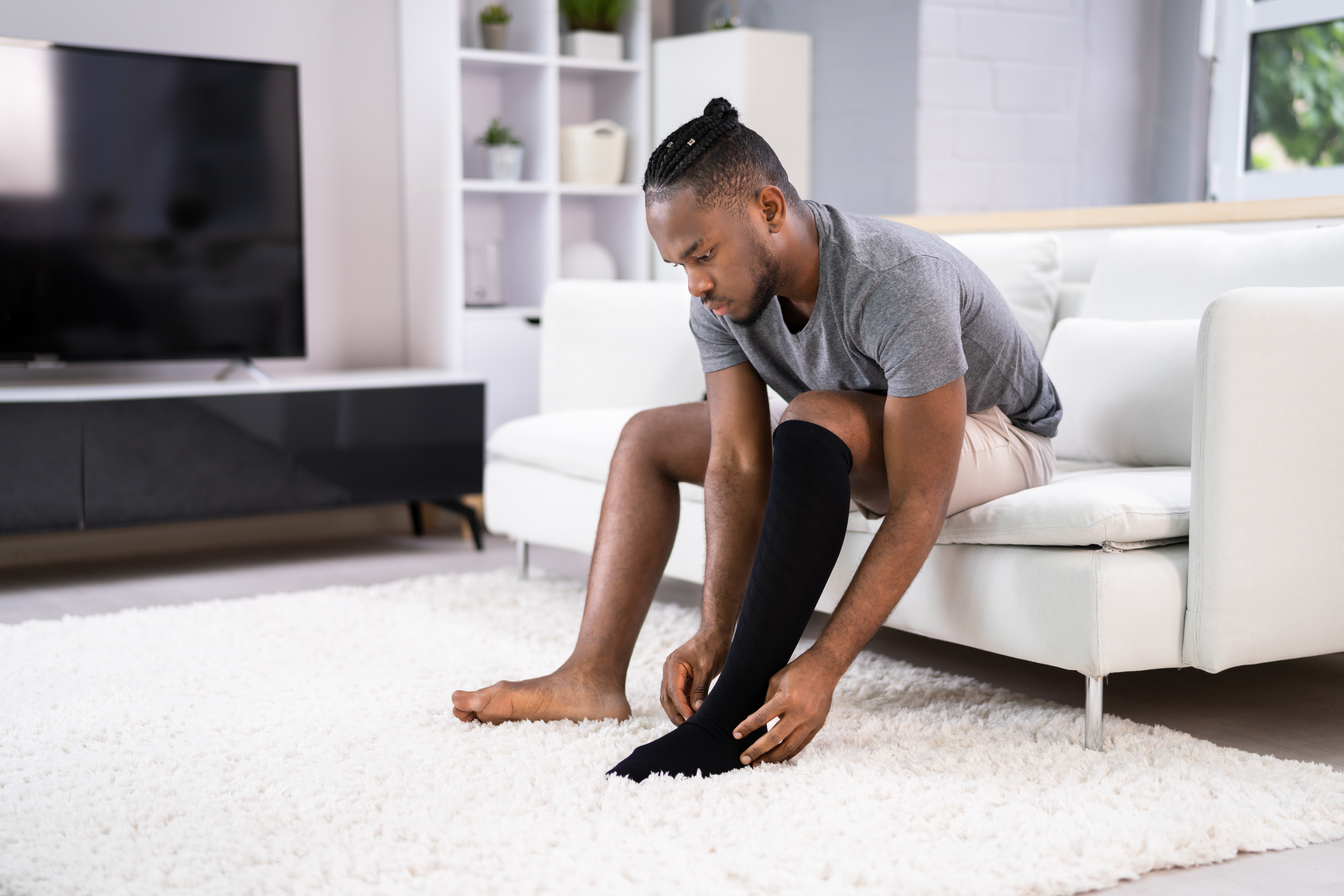 Man putting medical compression stockings on his legs.