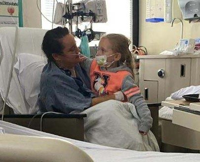 Kasey Watson talking to her young daughter who she cradles in her arms, while recovering in her hospital bed .