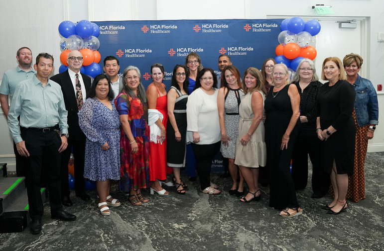 Group of people stand smiling.