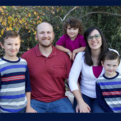 Sabrina Van Komen is seated with their husband and children in an outdoor setting.