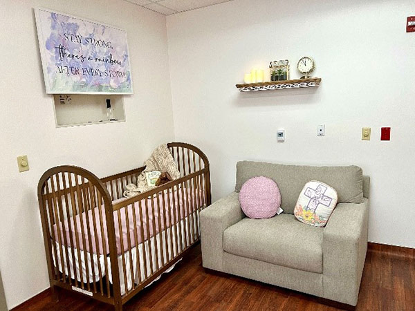 A crib and sofa in the Myles Family Care Room.