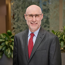 David S. Geckle, MD, FACS, newly appointed assistant chief medical officer at TriStar StoneCrest Medical Center, wearing a dark suit, red tie, and glasses, smiling in a professional indoor setting.
