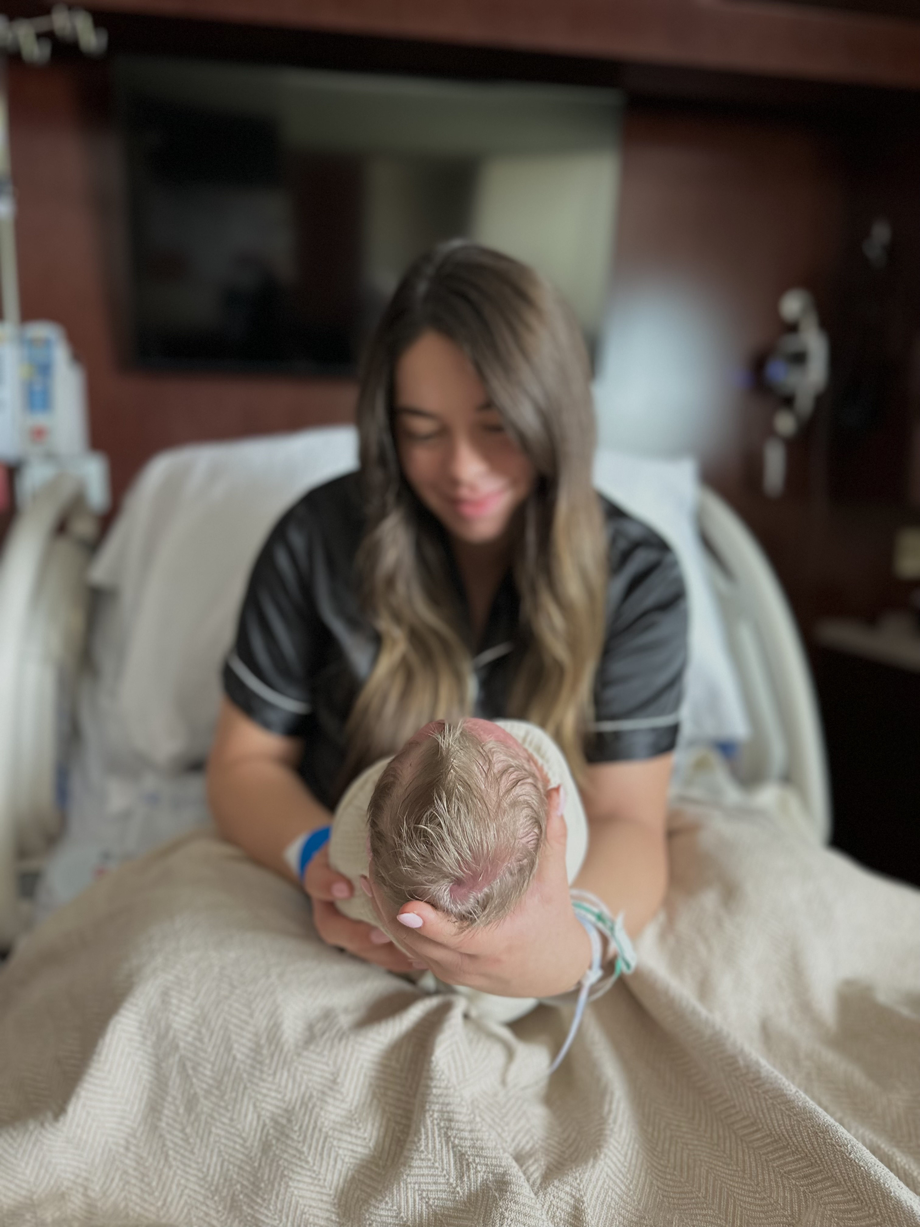 Katherine Durtschi holding baby Maverick and smililng in hospital bed.