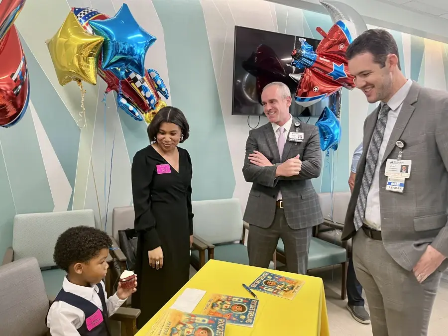 Male and female hospital staff surround young boy Payton seated at a table with books.