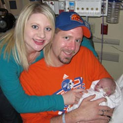 Lyndsay wraps her arms around her husband Michael, who is holding their newborn son, Landon.