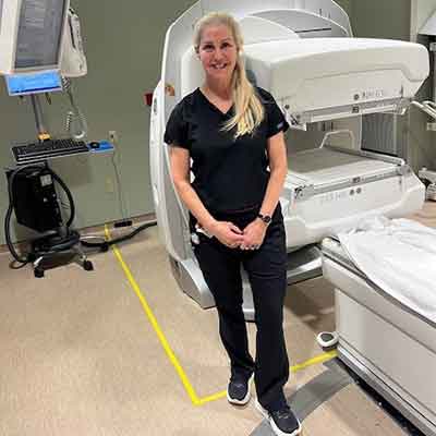 Lynn Sauro poses in front of a hospital machine.