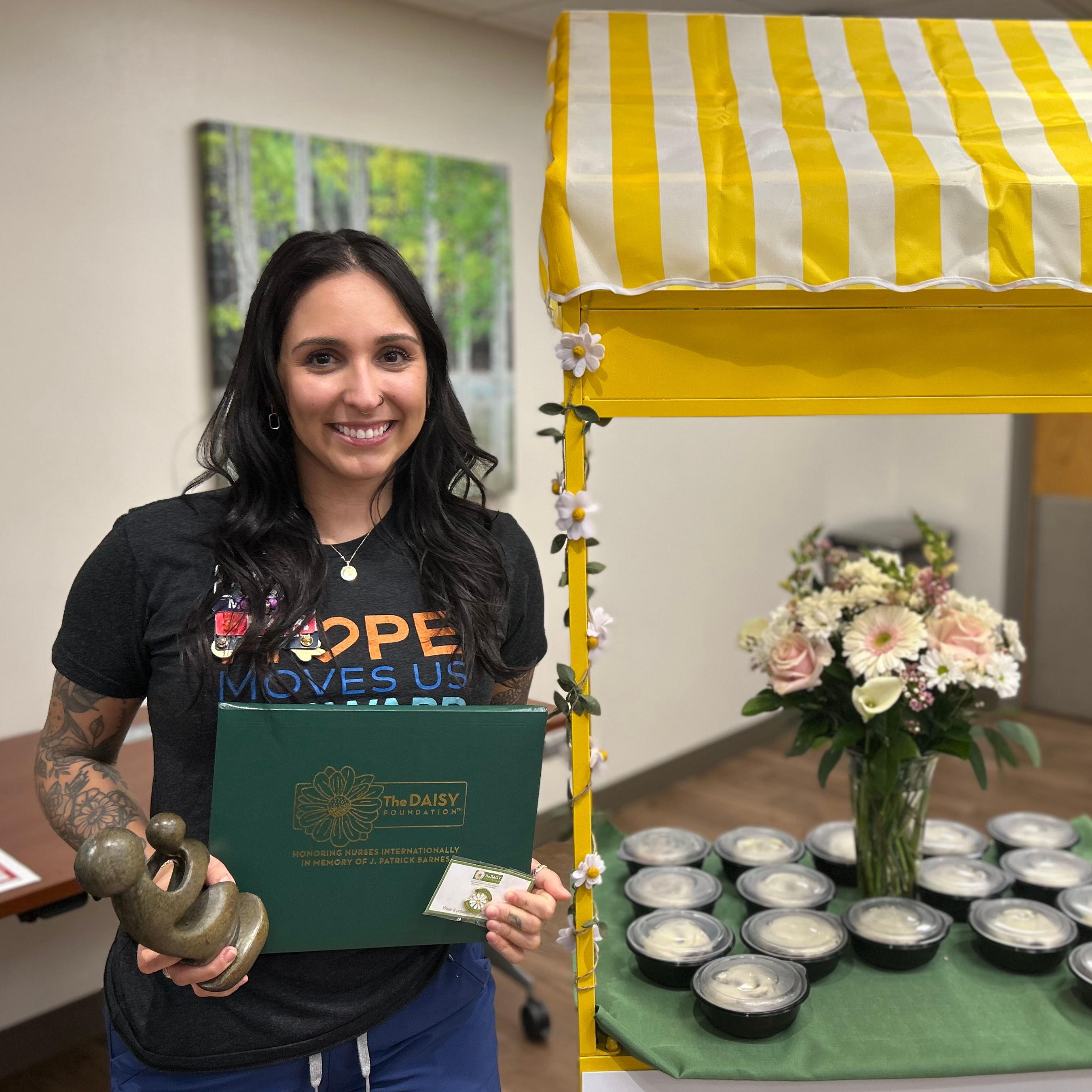 2025 Daisy Nurse Leader Shanaya Sharpe standing, smiling and holding her award.