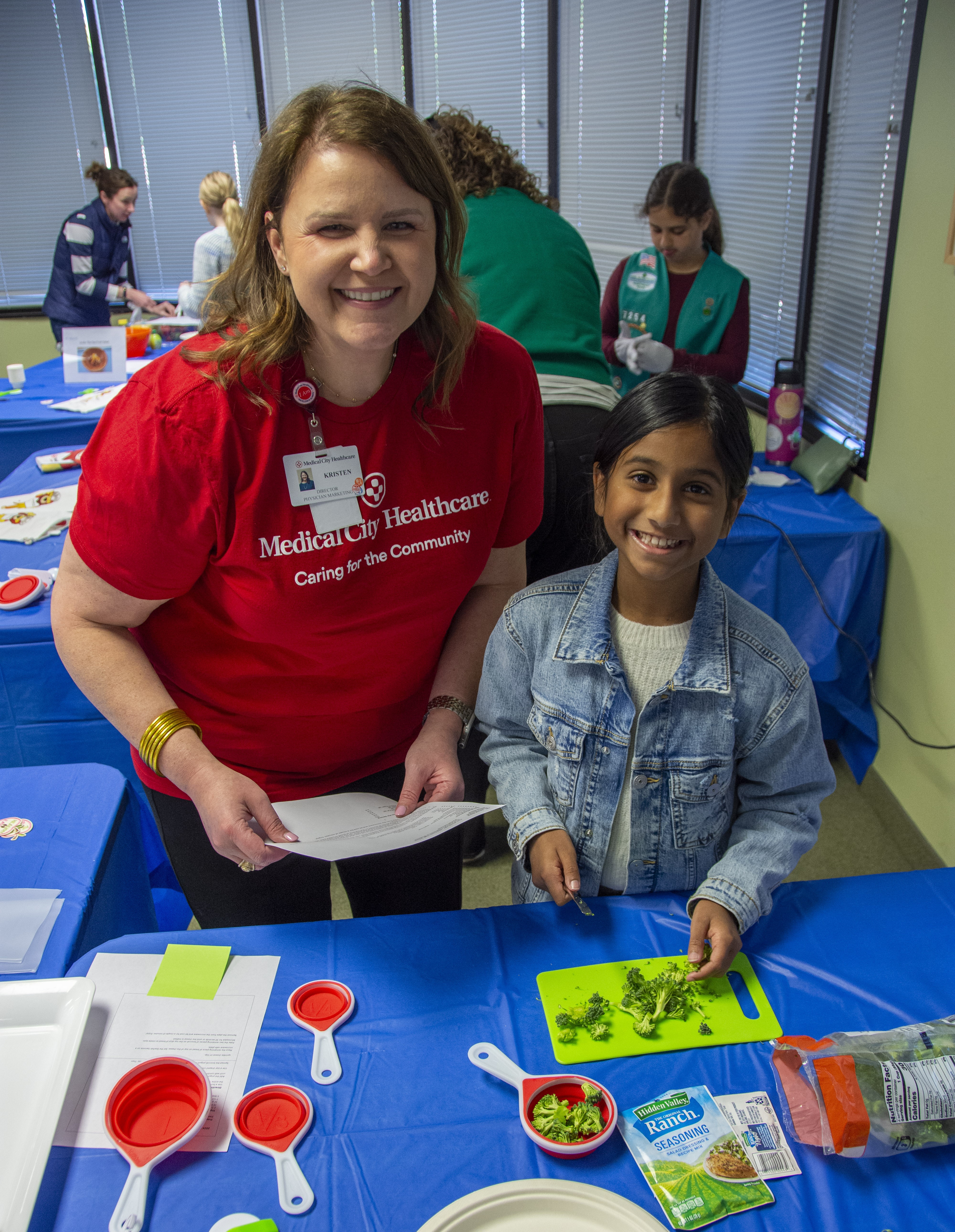 A staff member and a young girl working on a healthy recipe.